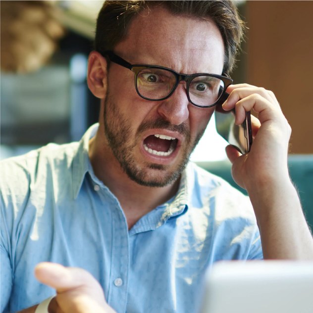 Napięty mężczyzna rozmawiający przez telefon przy laptopie